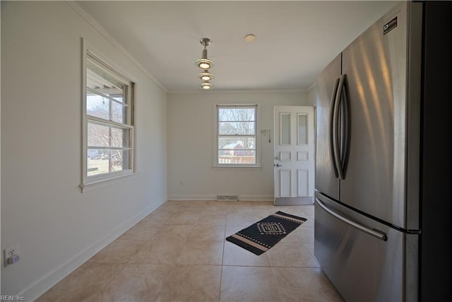 kitchen with light tile patterned floors, freestanding refrigerator, baseboards, and ornamental molding