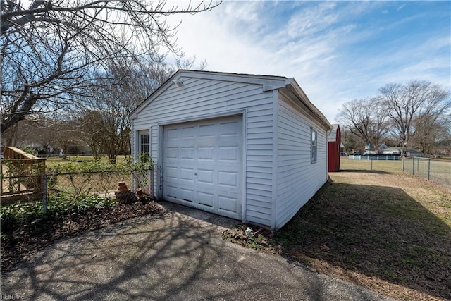 detached garage featuring aphalt driveway and fence