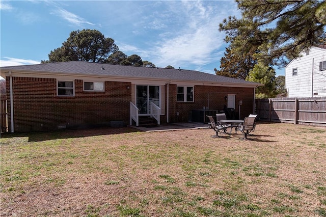 back of house featuring a lawn, entry steps, a patio, brick siding, and fence private yard