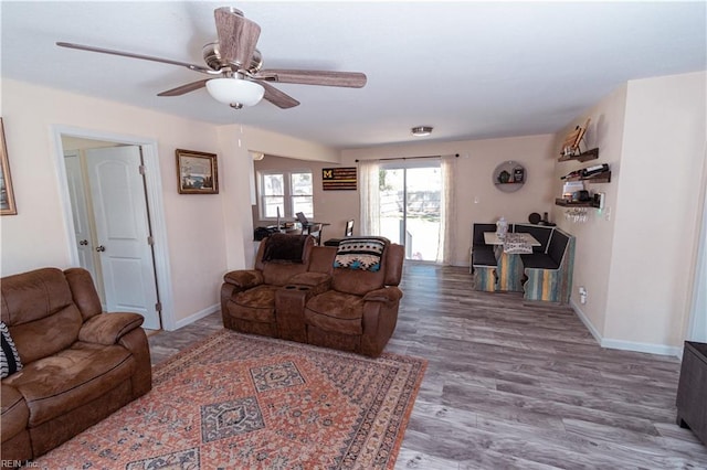 living area featuring a ceiling fan, wood finished floors, and baseboards