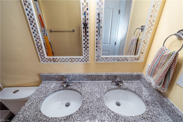 bathroom featuring double vanity, toilet, and a sink