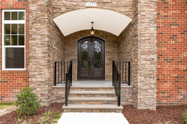 view of exterior entry featuring french doors and brick siding