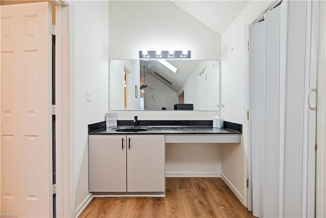 bathroom featuring a textured ceiling, wood finished floors, lofted ceiling, ceiling fan, and vanity