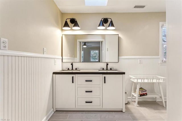 full bath with double vanity, visible vents, wainscoting, and a sink