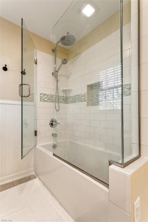 full bathroom featuring combined bath / shower with glass door, a wainscoted wall, and tile patterned floors