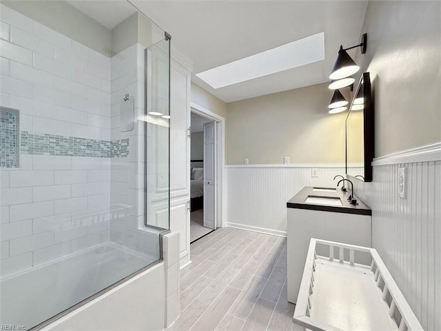 ensuite bathroom featuring a wainscoted wall, wood tiled floor, ensuite bathroom, shower / bath combination with glass door, and vanity