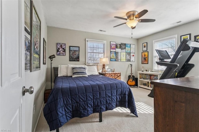 carpeted bedroom featuring visible vents, multiple windows, and ceiling fan