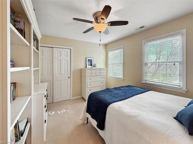 bedroom featuring visible vents, multiple windows, light colored carpet, and a closet