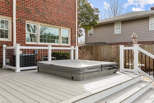 wooden deck featuring a covered hot tub and fence