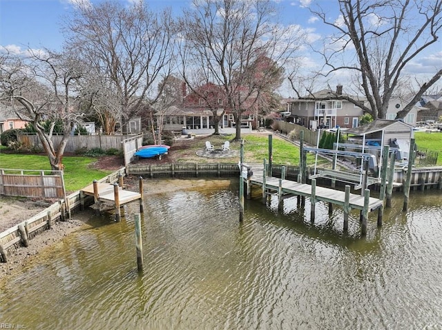 view of dock featuring a residential view, a water view, a lawn, and fence