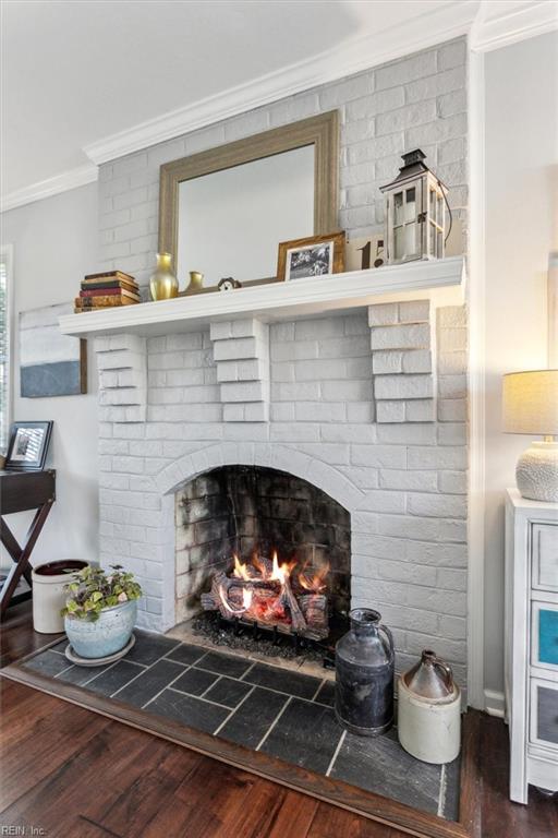 interior details featuring a brick fireplace, wood finished floors, and crown molding