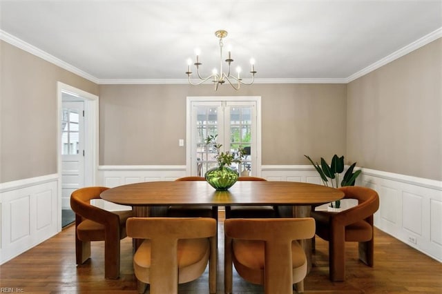 dining space with an inviting chandelier, wood finished floors, a wainscoted wall, and ornamental molding