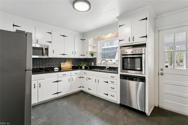 kitchen featuring dark countertops, open shelves, appliances with stainless steel finishes, and a sink