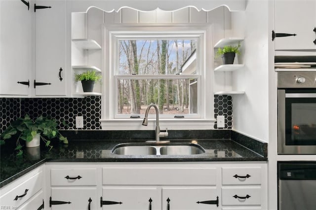 kitchen featuring a sink, open shelves, white cabinetry, and oven