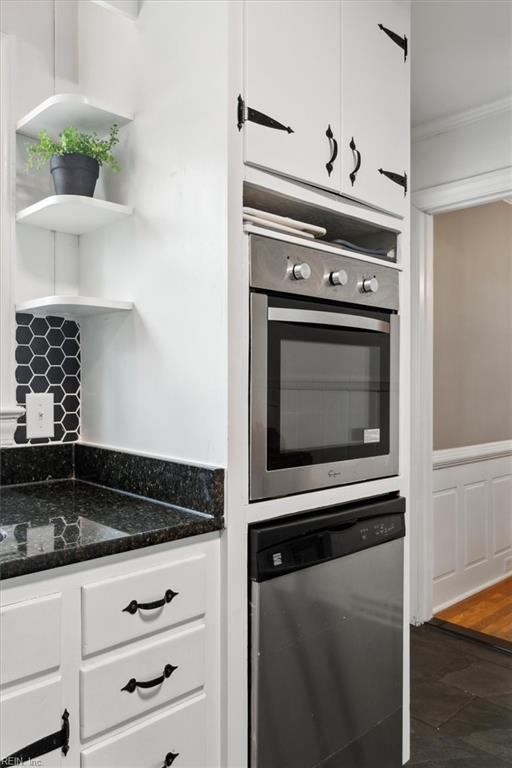 kitchen featuring ornamental molding, dark stone countertops, appliances with stainless steel finishes, white cabinetry, and open shelves