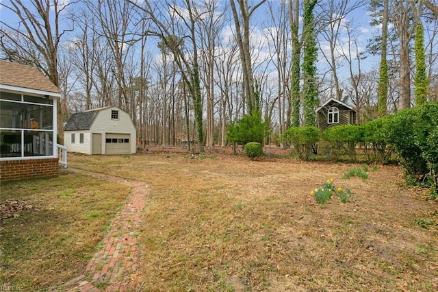 view of yard featuring a detached garage, an outdoor structure, and a sunroom