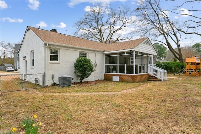 back of house featuring a playground, a gate, a yard, and central AC