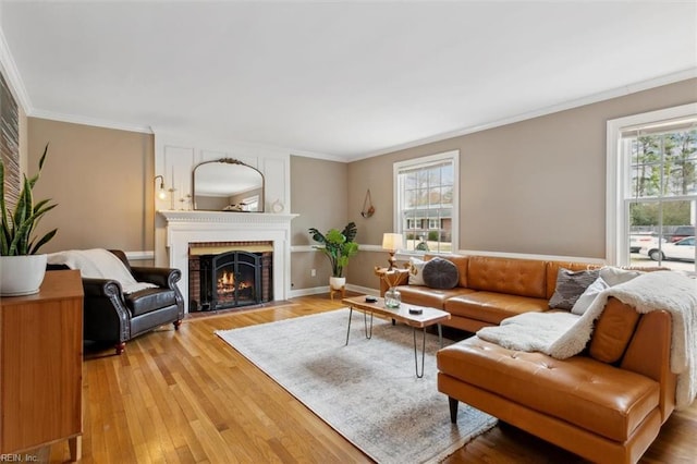 living area featuring a fireplace, light wood-type flooring, baseboards, and ornamental molding