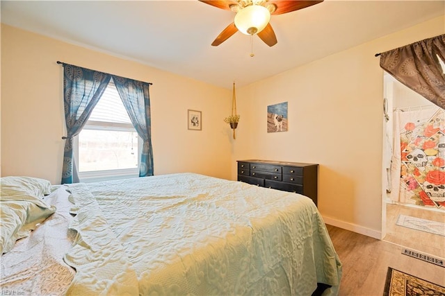 bedroom with a ceiling fan, wood finished floors, and baseboards