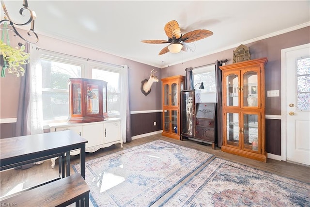 sitting room featuring ceiling fan, wood finished floors, a wainscoted wall, and ornamental molding