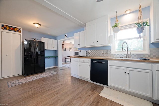 kitchen featuring white cabinetry, black appliances, light wood finished floors, and decorative backsplash