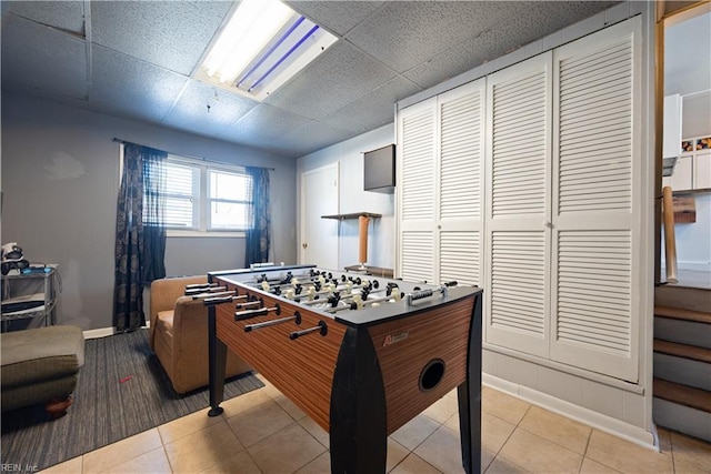 game room featuring light tile patterned floors, a drop ceiling, and baseboards