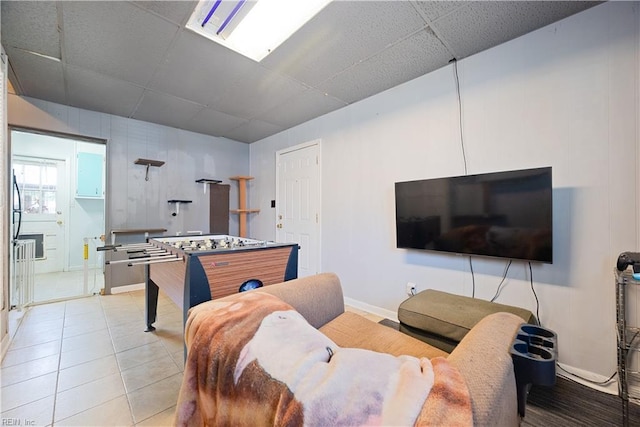 living area featuring light tile patterned floors, a paneled ceiling, and baseboards