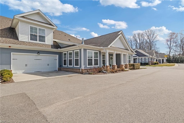 view of front facade with aphalt driveway, an attached garage, and roof with shingles