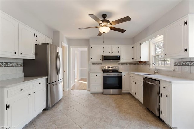 kitchen featuring decorative backsplash, white cabinetry, stainless steel appliances, and a sink