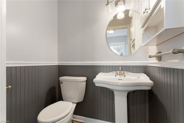 half bath featuring toilet and a wainscoted wall