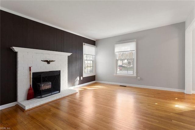 unfurnished living room with light wood-style flooring, a fireplace, and baseboards