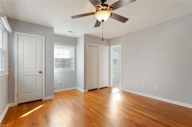 unfurnished bedroom featuring visible vents, multiple closets, light wood-style floors, and baseboards