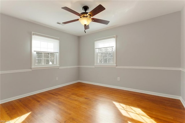 empty room with light wood-type flooring, visible vents, plenty of natural light, and baseboards