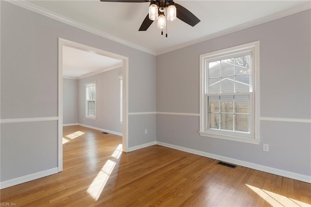 spare room with visible vents, baseboards, crown molding, and light wood-style floors