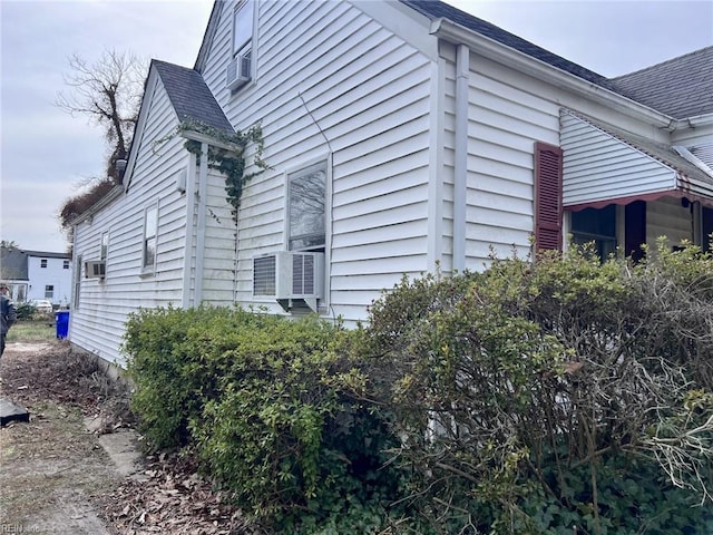 view of home's exterior featuring cooling unit and a shingled roof