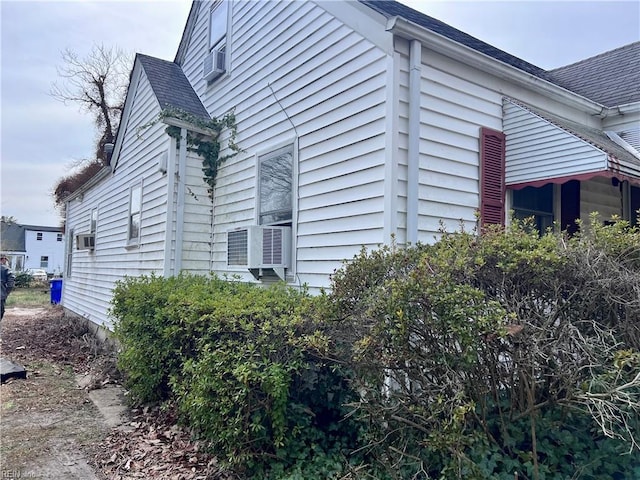 view of side of property featuring cooling unit and roof with shingles