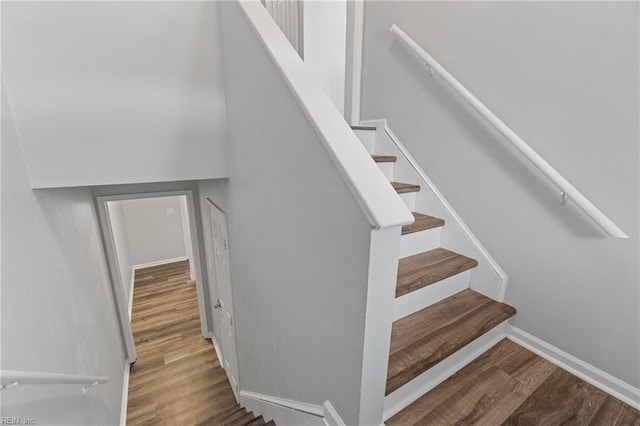 staircase with baseboards and wood finished floors