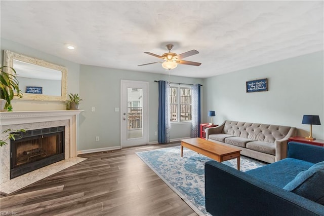 living room with ceiling fan, wood finished floors, baseboards, and a premium fireplace