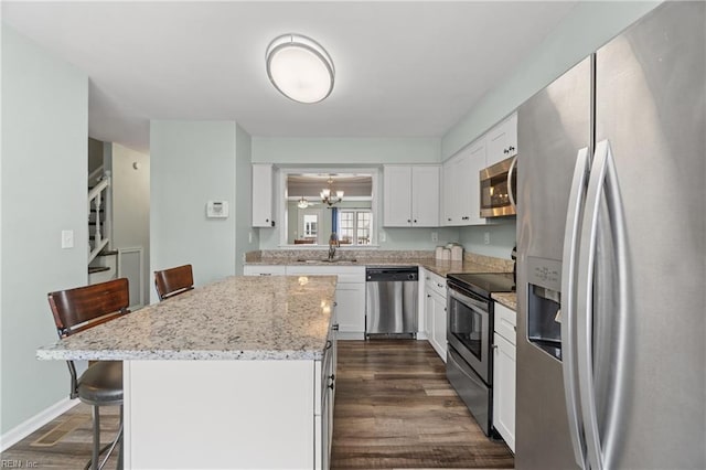 kitchen with a center island, a kitchen bar, stainless steel appliances, white cabinetry, and a sink