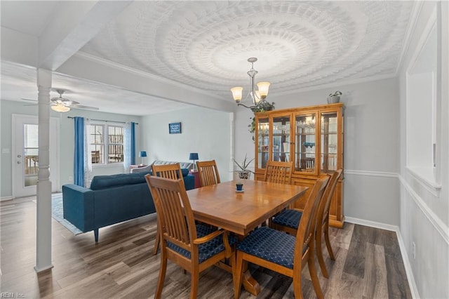 dining space with baseboards, wood finished floors, ornamental molding, and ceiling fan with notable chandelier