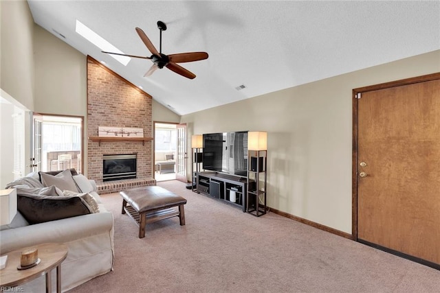 living area featuring a ceiling fan, visible vents, a skylight, a brick fireplace, and light colored carpet