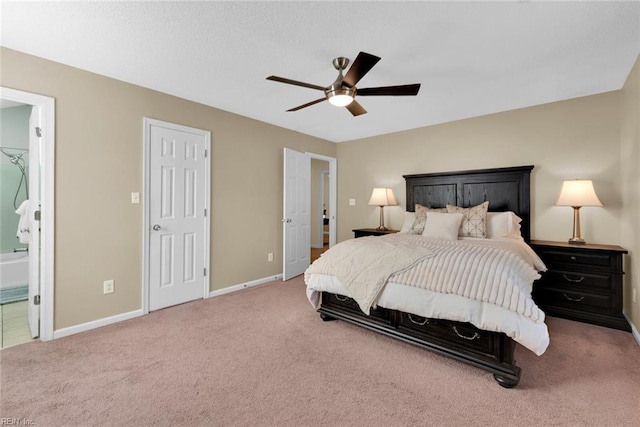 carpeted bedroom featuring ensuite bath, baseboards, and a ceiling fan