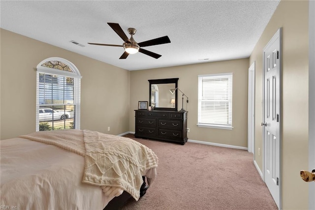 bedroom with carpet flooring, multiple windows, a textured ceiling, and visible vents