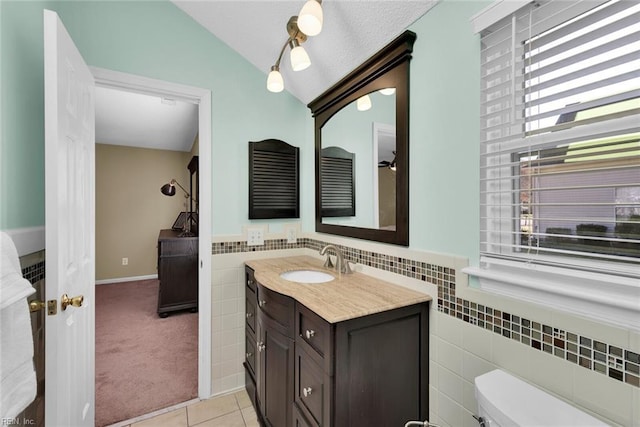 bathroom featuring vanity, lofted ceiling, tile walls, toilet, and tile patterned floors