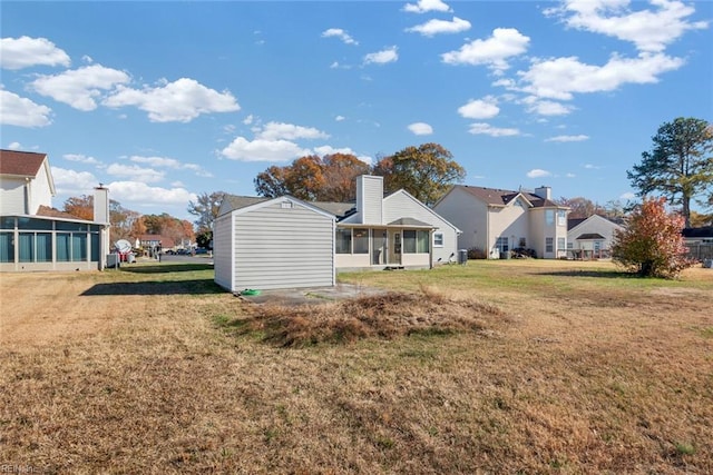 rear view of property with a yard, a residential view, a sunroom, and a chimney