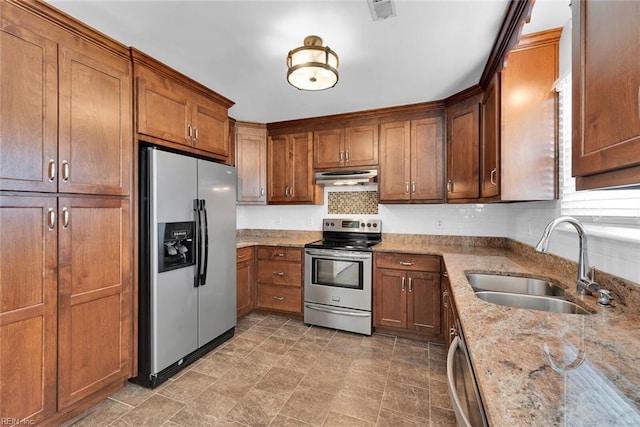 kitchen featuring under cabinet range hood, stainless steel appliances, brown cabinets, and a sink