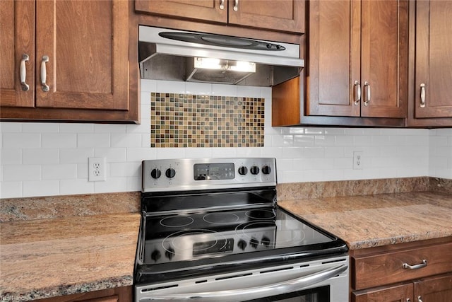 kitchen with under cabinet range hood, electric range, and tasteful backsplash