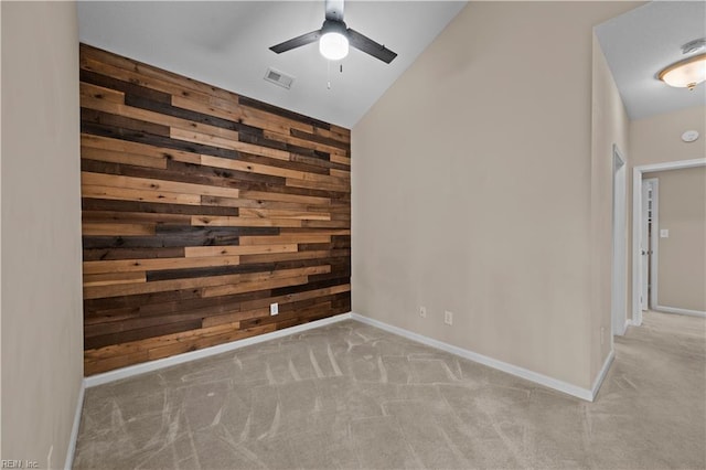 spare room with wooden walls, visible vents, an accent wall, carpet floors, and a ceiling fan