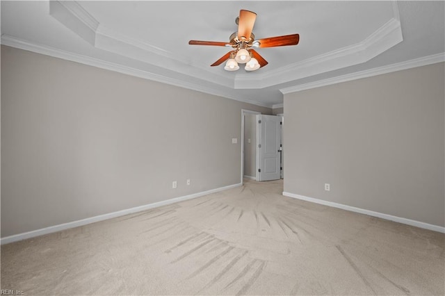 spare room featuring a raised ceiling, baseboards, and ornamental molding