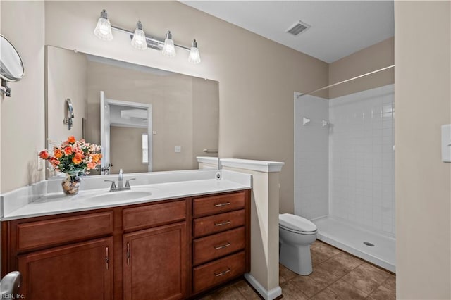 bathroom with visible vents, toilet, a tile shower, tile patterned flooring, and vanity